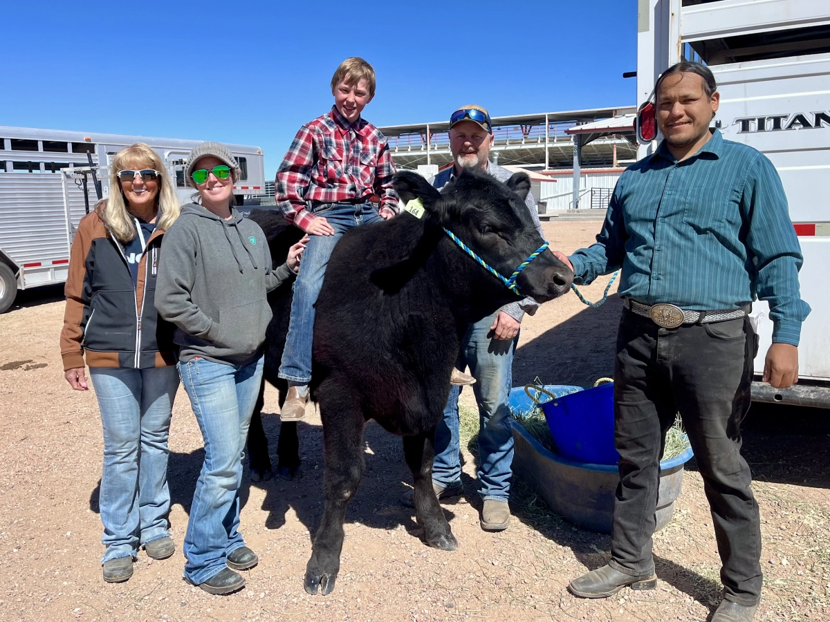 Family posing around a boy sitting on a black steer